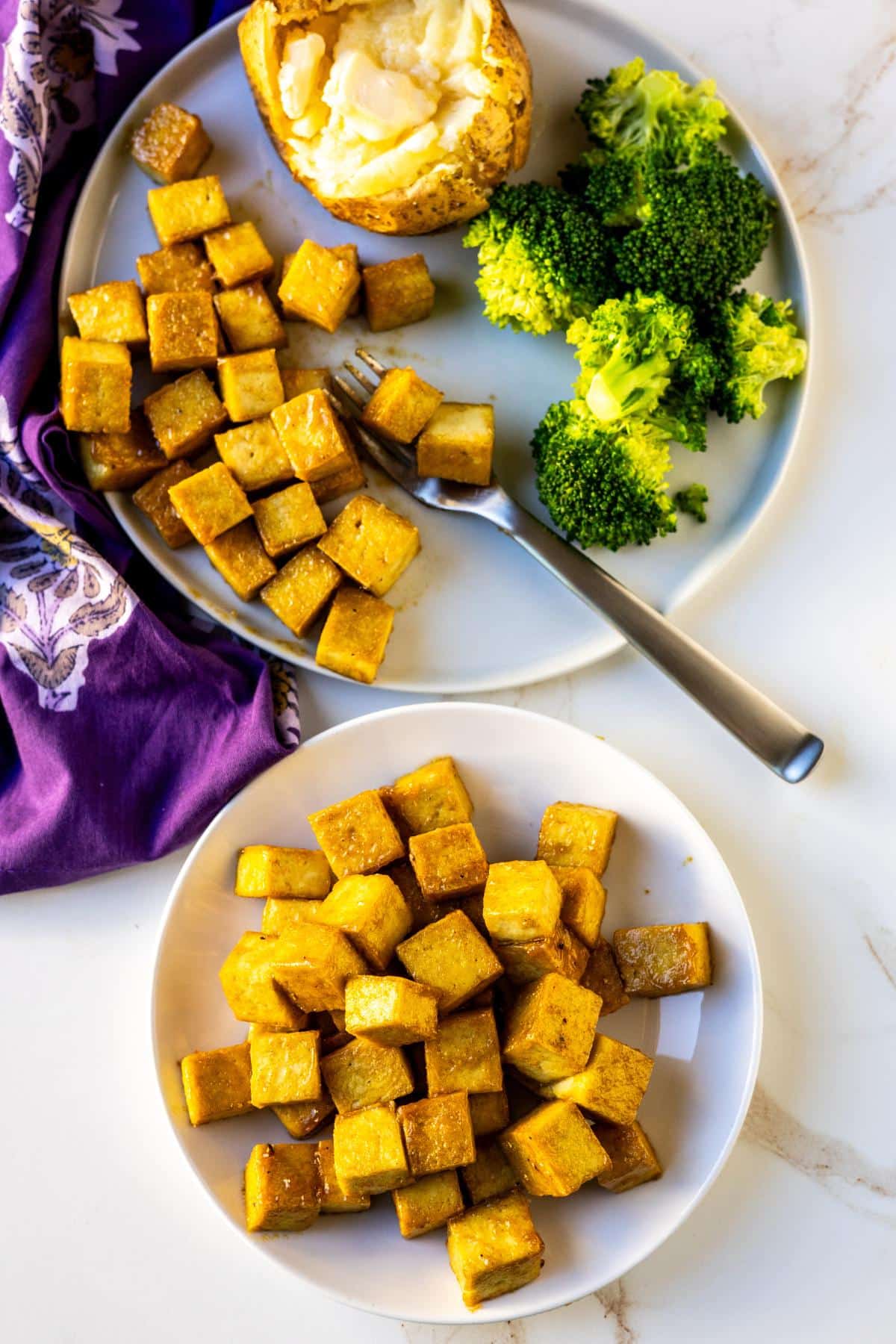 Dinner plate with maple Dijon cubes, steamed broccoli, and a baked potatoes and a serving plate of tofu.