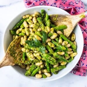 Bowl of asparagus white bean salad with lemon pesto dressing next to a pink napkin.