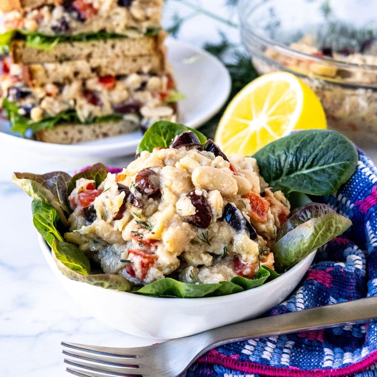 Smashed white bean salad on a bowl of lettuce and in a sandwich.