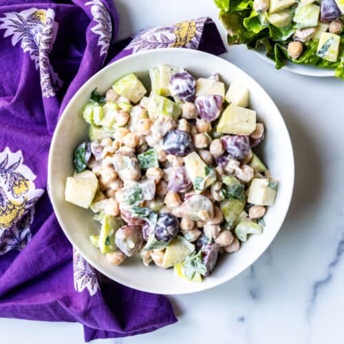 Bowl of chickpea Waldorf salad with a purple napkin alongside it.