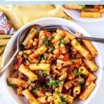 Bowl of rigatoni in a white bean tomato sauce with Kalamata olives and fresh parsley, with text overlay: White Bean Tomato Pasta with Olives.