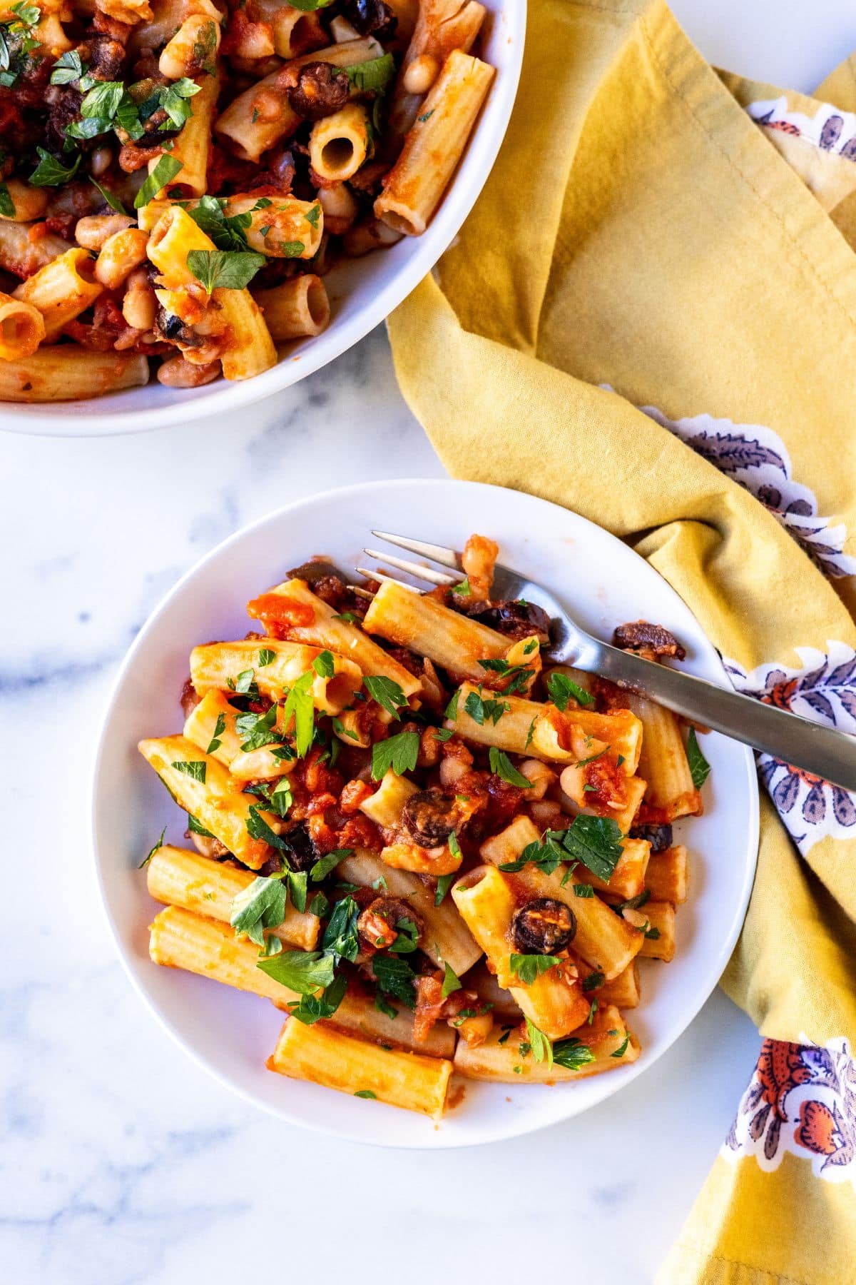 A serving of rigatoni tossed with white bean tomato and olive sauce.