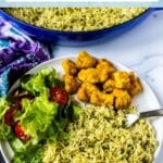 Dinner plate with pesto rice, salad, and tofu, with text overlay: Baked Basmati Rice with Pesto.