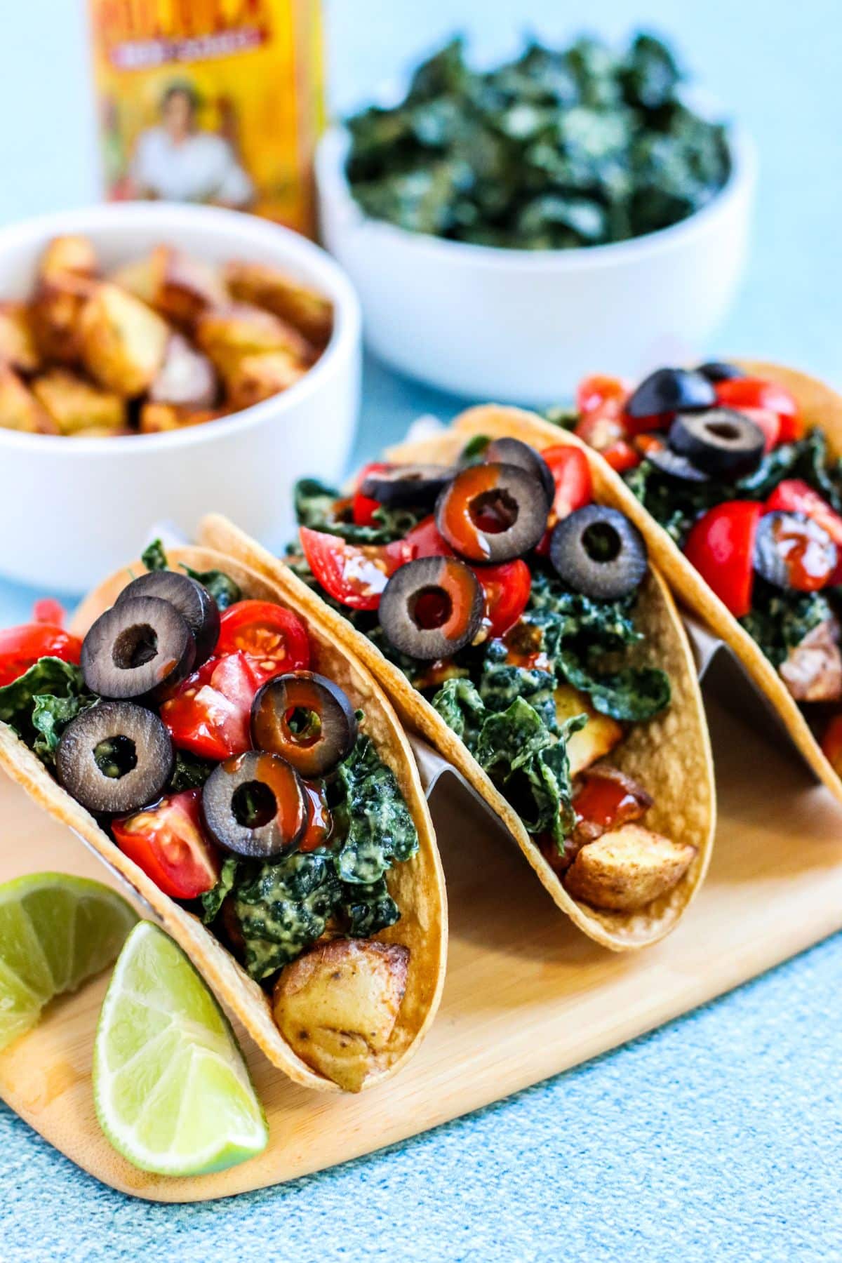 Potato tacos topped with avocado massaged kale, tomatoes, olives, and hot sauce.