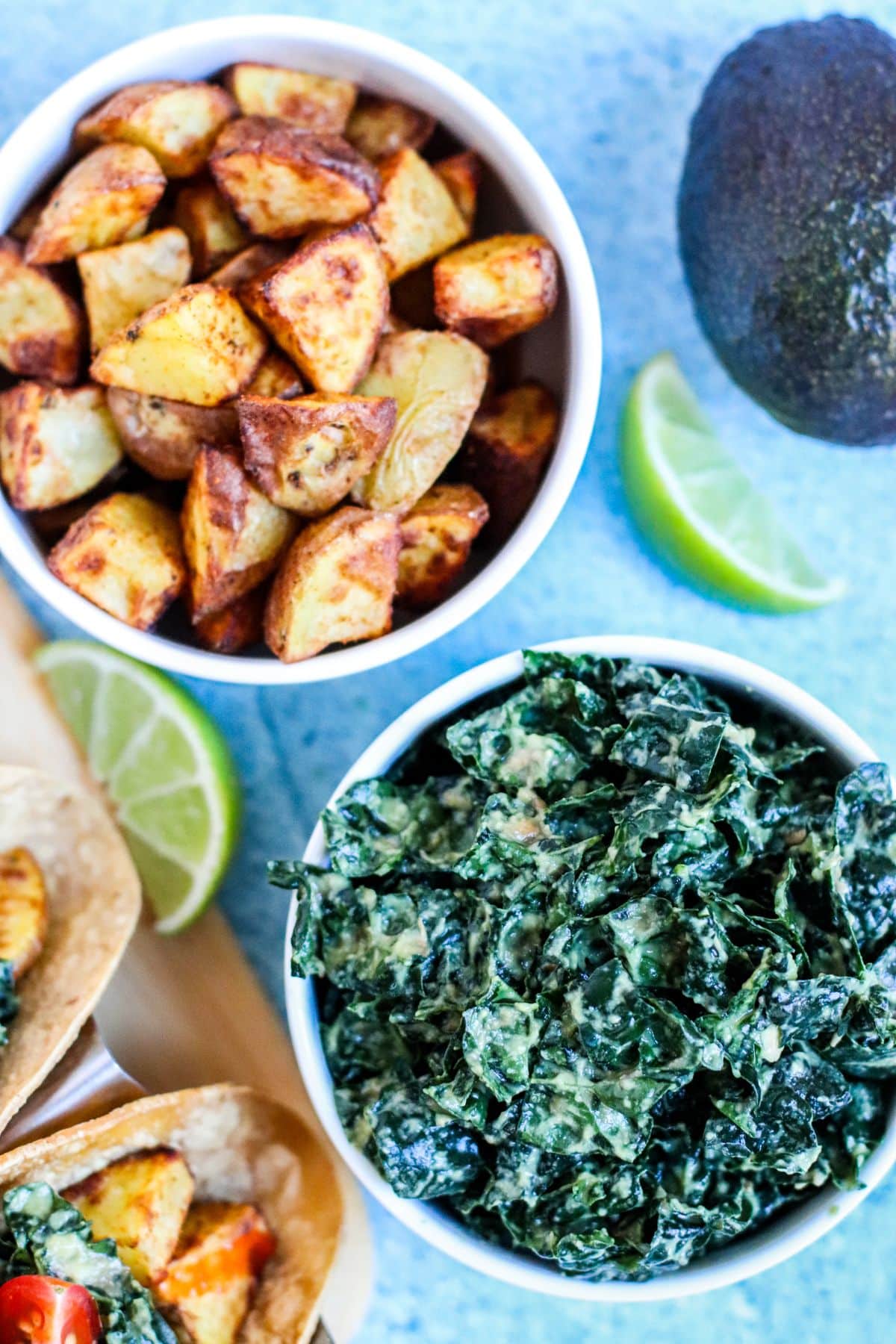 Bowls of seasoned roasted potato chunks and avocado-massaged kale.
