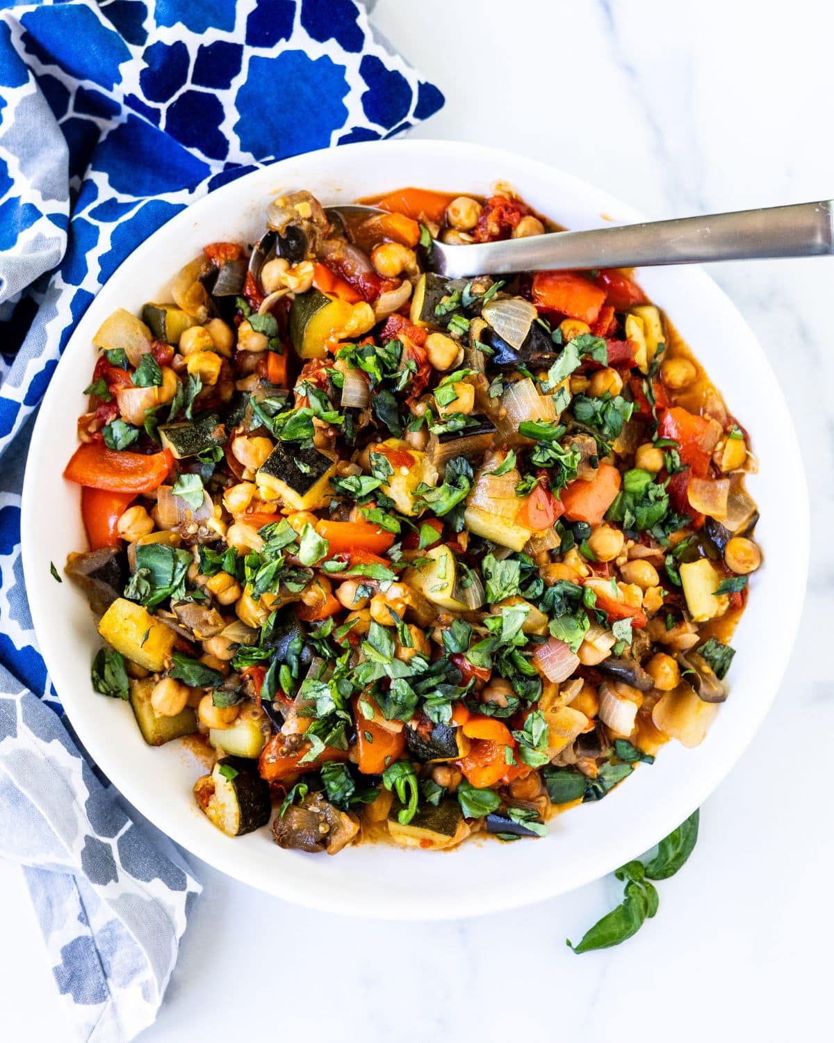 Roasted chickpea ratatouille in a serving bowl with a spoon.