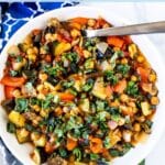 Bowl of ratatouille garnished with fresh basil, with text overlay: Roasted Chickpea Ratatouille Casserole.