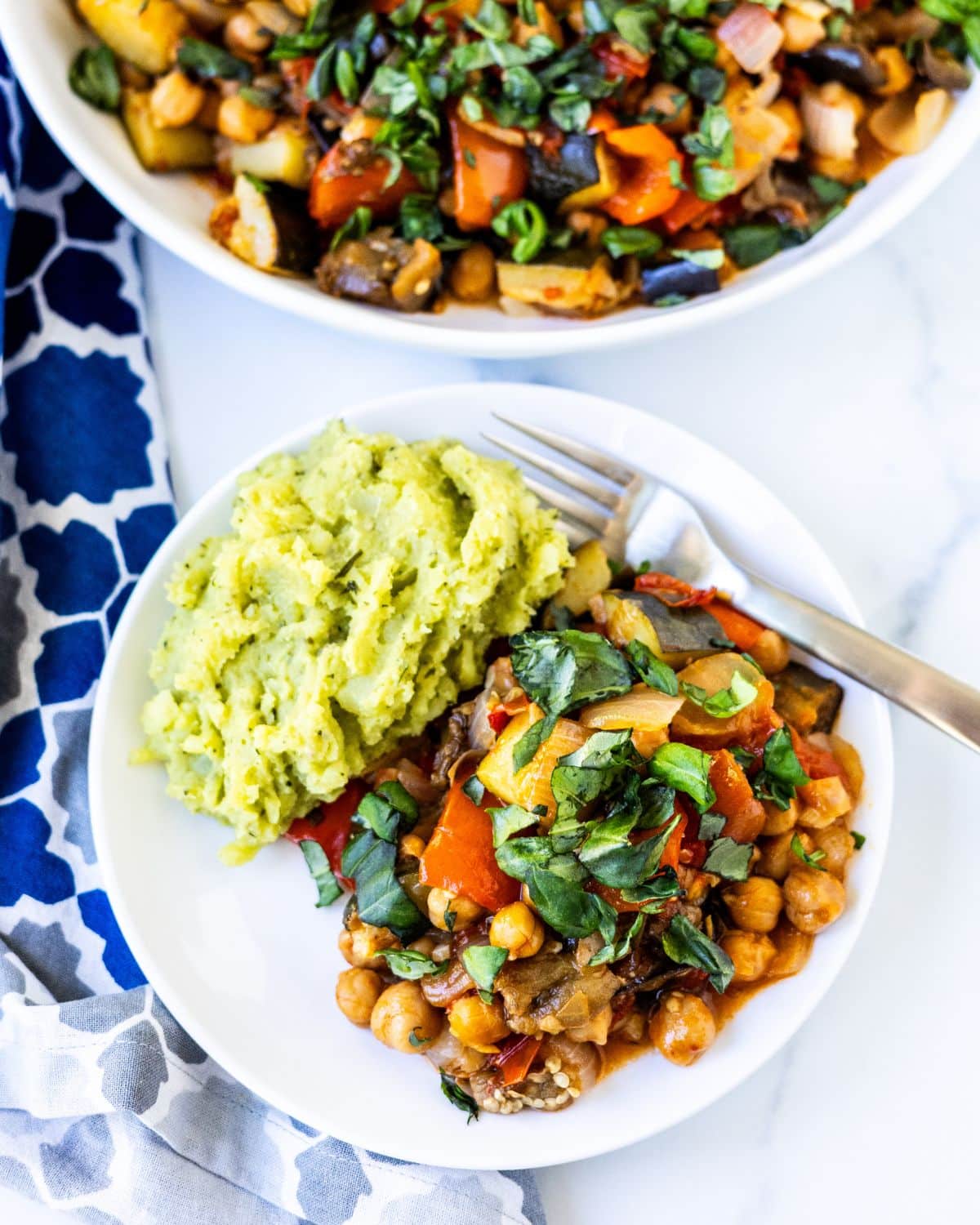 A dinner plate with mashed potatoes and chickpea ratatouille with a fork alongside.