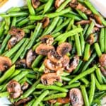 Platter of greens beans and mushrooms, with text overlay: Sauteed Green Beans Recipe with Mushrooms.