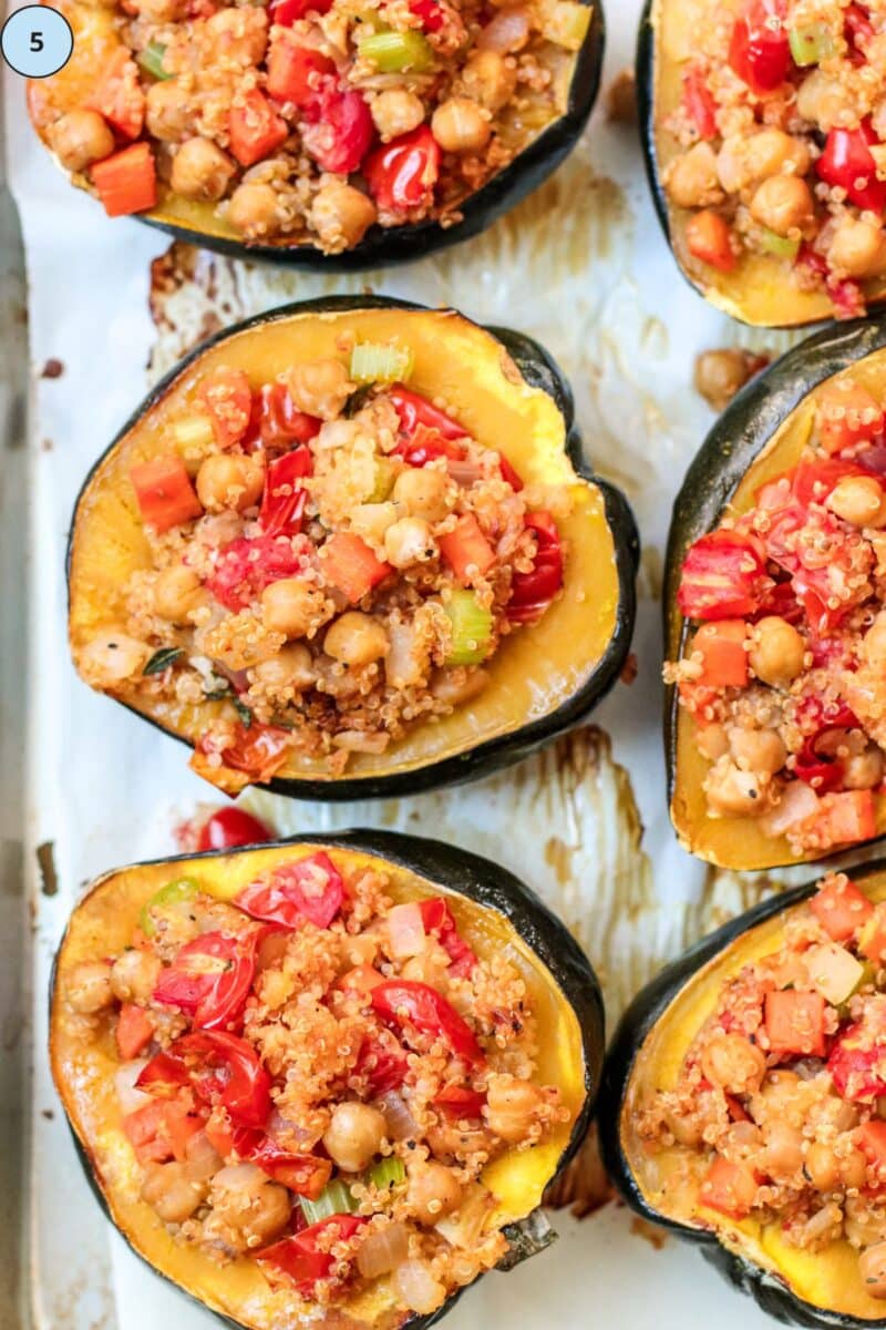 Baked stuffed acorn squash halves on a sheet pan.