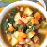 Bowl of chunky soup with vegetables and white beans, with text overlay: Vegan Vegetable Soup with Beans and Potatoes.
